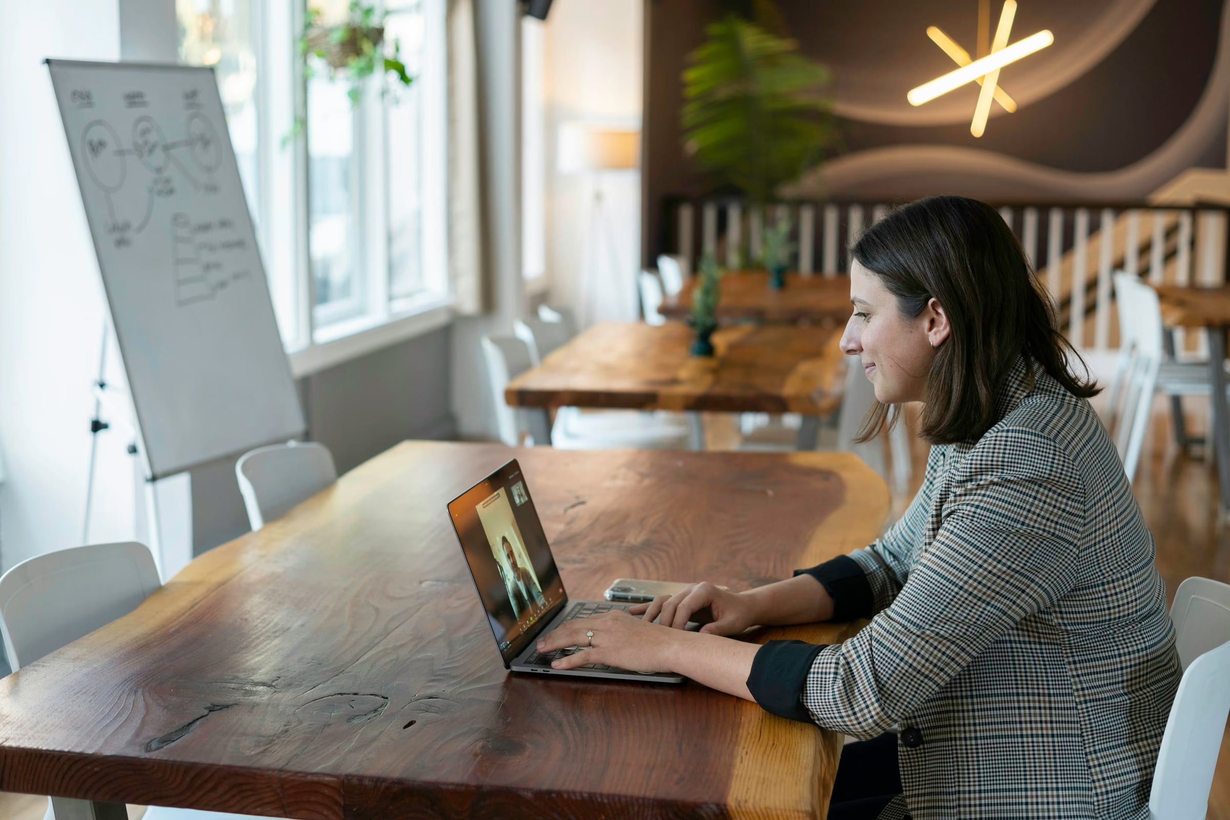 A woman on a video call at a long wooden table