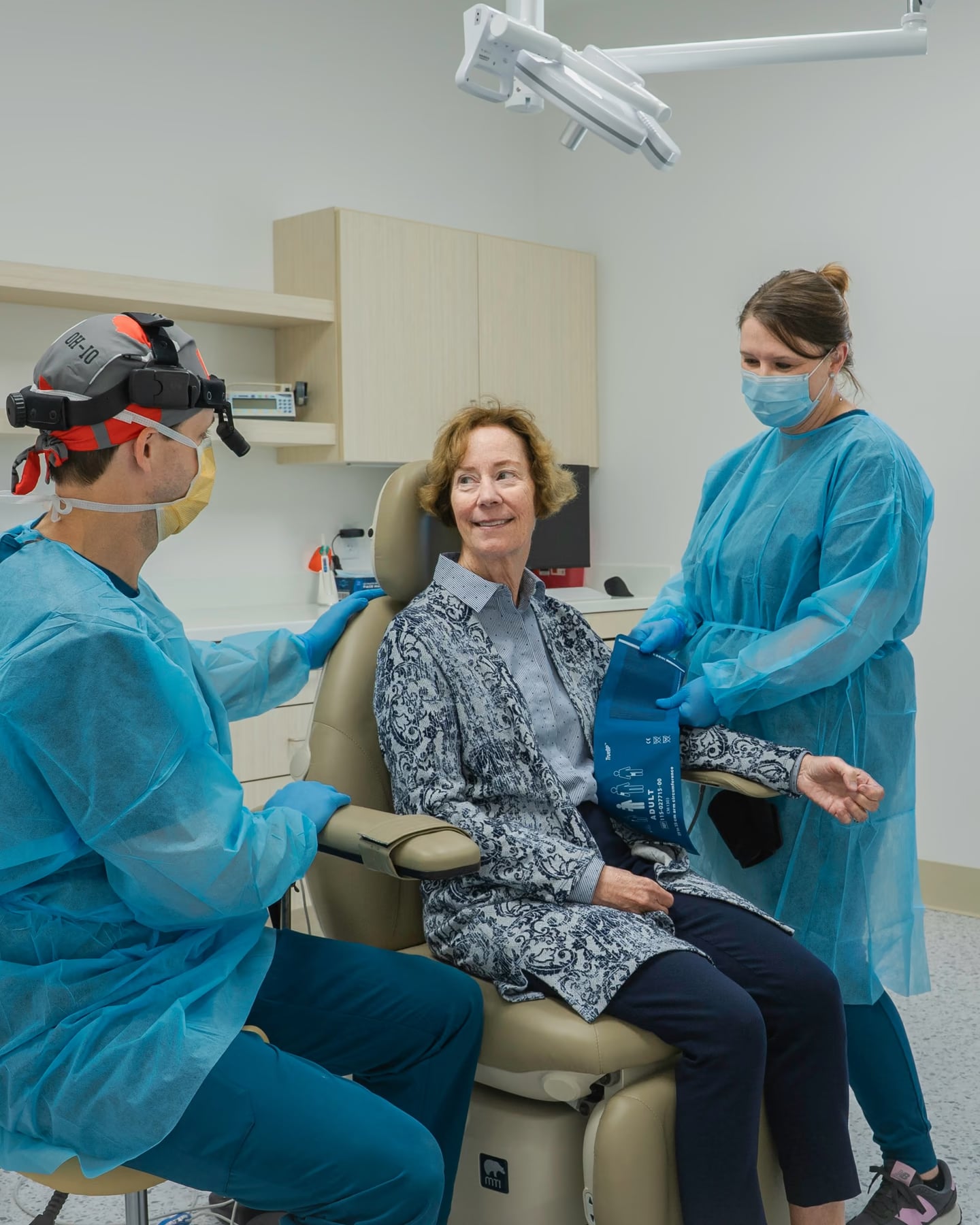 A dentist and an assistant talking with a patient in the treatment chair